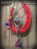 "Sacred Rio" is a red shoe adorned with a sacred heart and colorful dangles and lots of bling! 